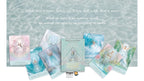 A set of illustrated oracle or tarot cards fanned out on a water-textured background, with the center card showing the book cover 'Healing Wounds' by Rebecca Camwell. The cards feature pastel watercolor artwork in blue, pink, and green tones, with inspirational text overlaid at the top.