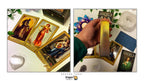 Dragon Tarot card deck set displayed with several illustrated cards laid out on a white surface and a hand holding a gold-edged deck box or card stack. The scene includes decorative crystals, flowers, and branded packaging, with the Dragon Tarot name visible at the top and bottom.
