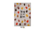 A Dragon Tarot art print featuring the quote 'YOU ARE NOT ALONE' in black text surrounded by colorful handprints in orange, yellow, brown, and red on a textured beige background. The print is centered on a white canvas with Dragon Tarot branding at the top and bottom.