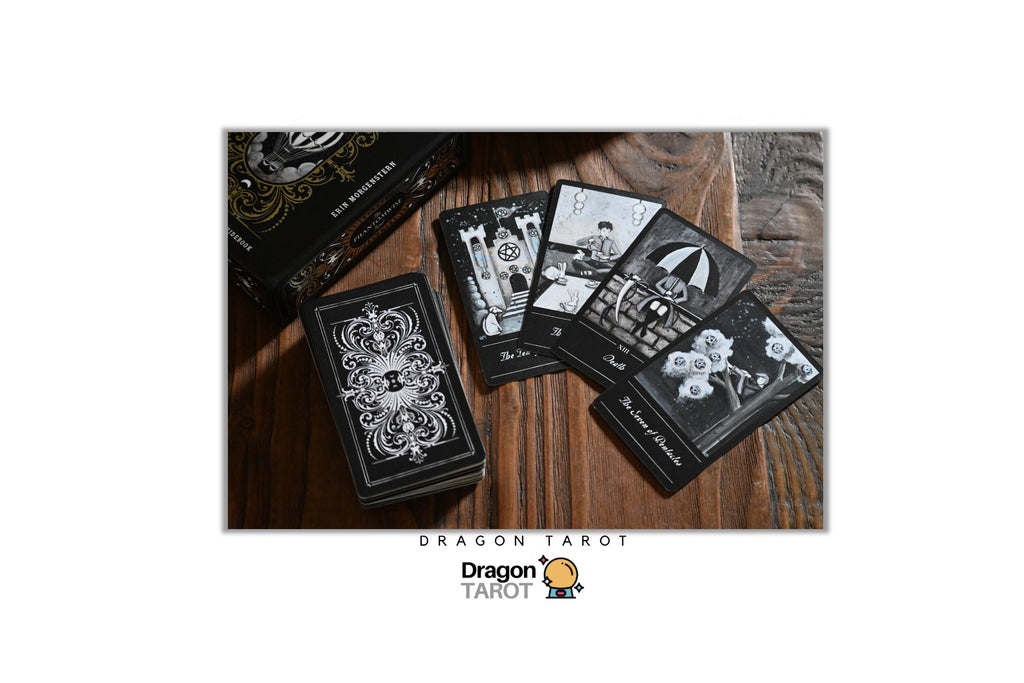 Dragon Tarot deck of cards with black and white illustrated cards and a black patterned box, displayed on a dark wooden surface. The image includes social media and brand text overlays at the top and bottom.