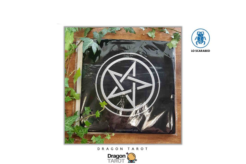 A black Dragon Tarot deck in plastic wrapping with a white pentagram symbol on the front, displayed on a wooden surface with green ivy leaves. The image has 'Dragon Tarot' branding and a 'LO SCARABIO' logo on a white background.