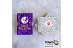 Super Attractor tarot deck by Gabrielle Bernstein, featuring a purple illustrated box and a stack of silver-backed cards with a red circular center, displayed on a light gray stone surface.