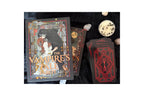 The Vampire's Stall Tarot deck shown with its illustrated box, several face-up cards, and a stack of face-down cards on a dark fabric background, alongside small decorative stones.