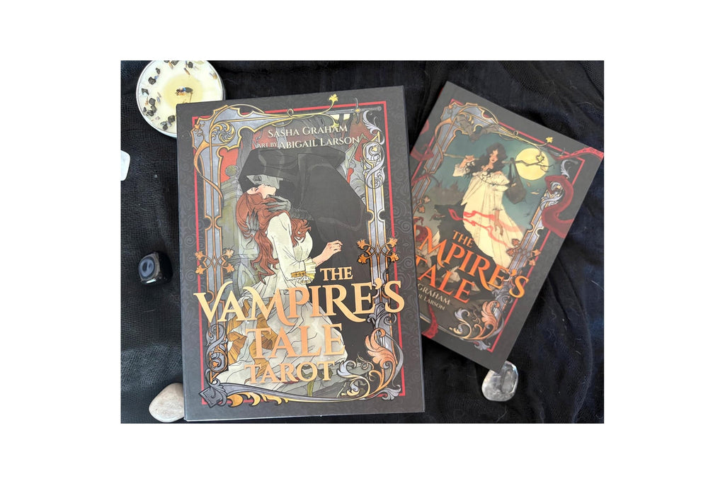 Two boxed board games, 'The Vampire's Tale' by Erica Coleman and Miguel Larrosa, displayed on a black fabric background with decorative stones and a clock.