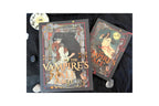 Two boxed board games, 'The Vampire's Tale' by Erica Coleman and Miguel Larrosa, displayed on a black fabric background with decorative stones and a clock.