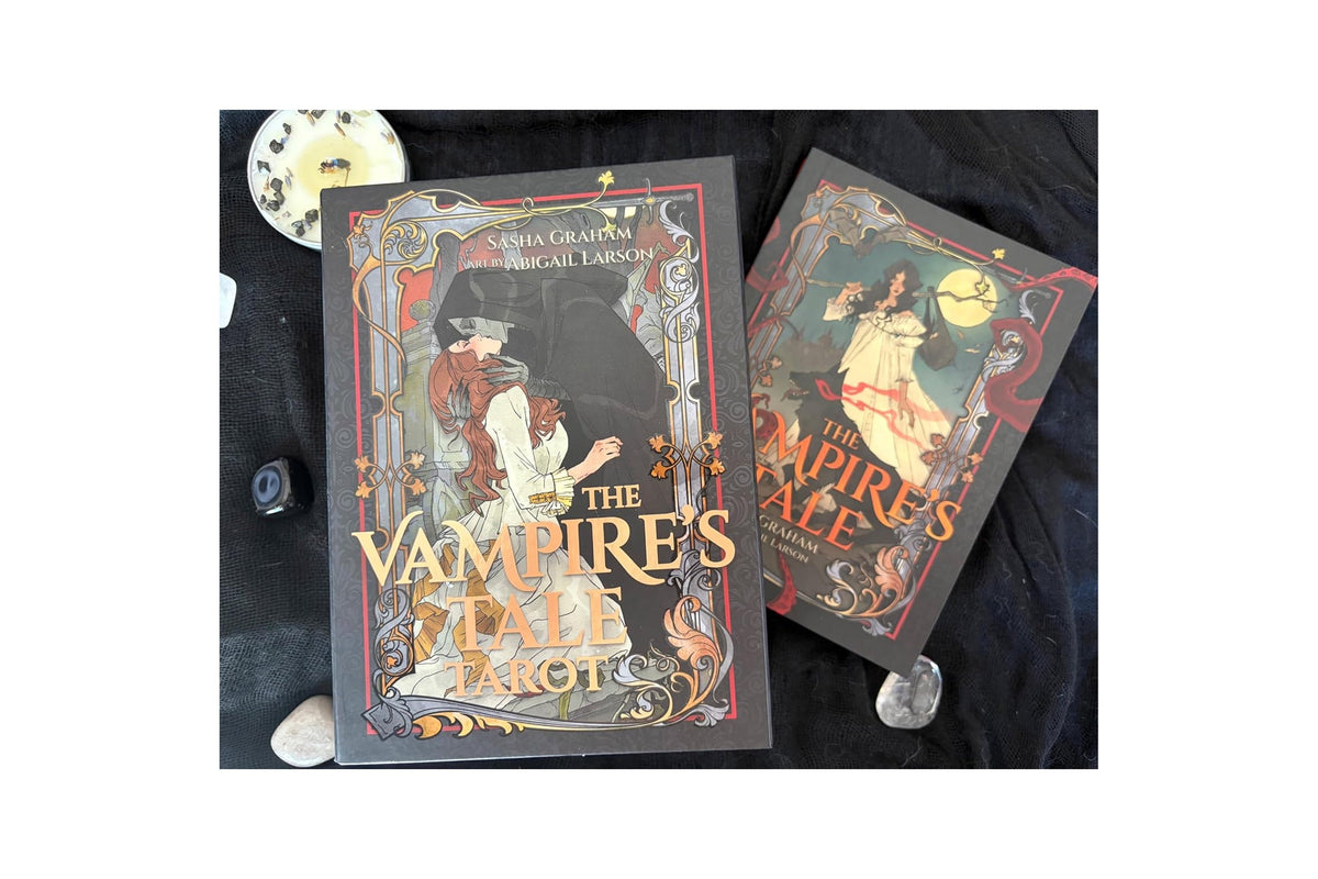 Two boxed board games, 'The Vampire's Tale' by Erica Coleman and Miguel Larrosa, displayed on a black fabric background with decorative stones and a clock.