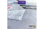 A stack of Dragon Tarot cards with a black and white floral patterned cover sits on a gray stone surface, with other cards and a purple box blurred in the background.