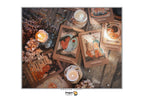 A flat-lay arrangement of illustrated tarot cards on a rustic wooden surface, surrounded by lit candles, dried flowers, and small decorative props. The cards feature vintage-style artwork with warm brown, beige, orange, and muted blue tones.