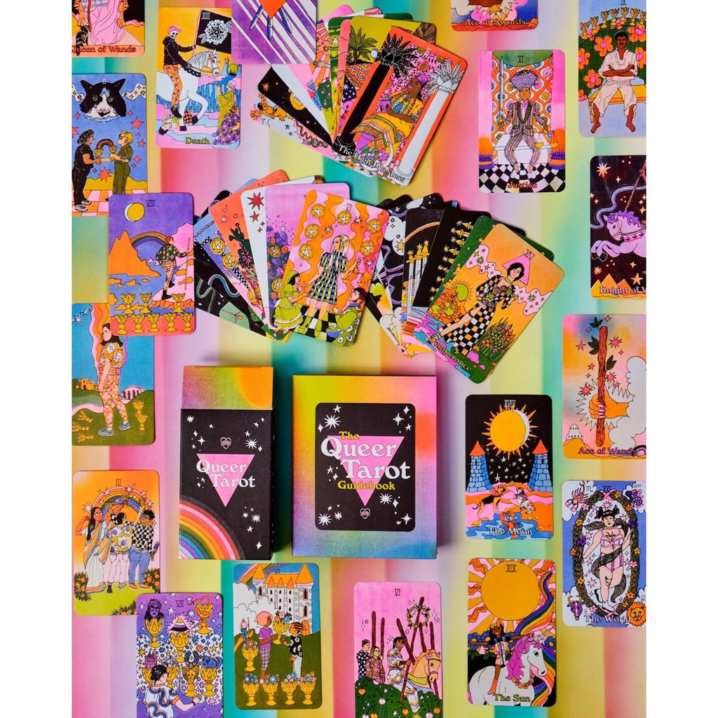 A colorful collection of illustrated tarot cards and card boxes arranged on a pastel rainbow background. The set includes multiple deck boxes and several fanned-out cards showing vibrant fantasy and celestial artwork in pink, yellow, blue, green, black, and white.