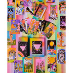 A colorful collection of illustrated tarot cards and card boxes arranged on a pastel rainbow background. The set includes multiple deck boxes and several fanned-out cards showing vibrant fantasy and celestial artwork in pink, yellow, blue, green, black, and white.