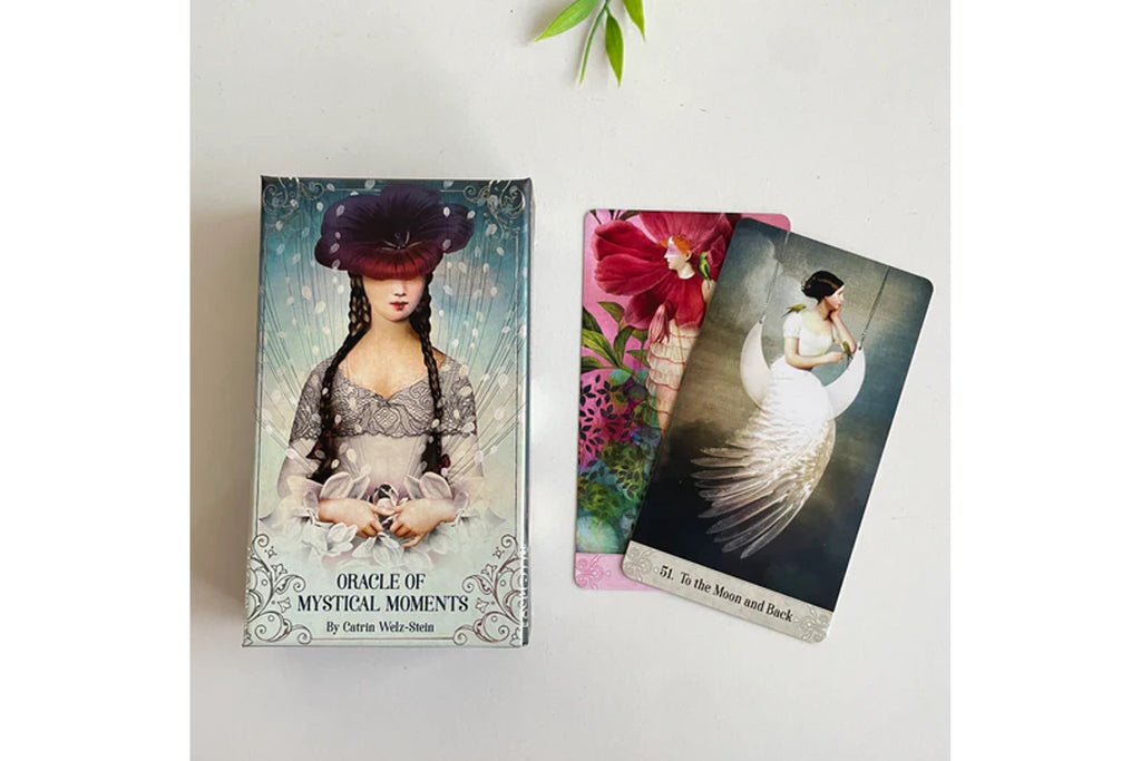 The 'Oracle of Mystical Moments' deck by Catherine White House, showing the illustrated box and two cards on a light gray surface.