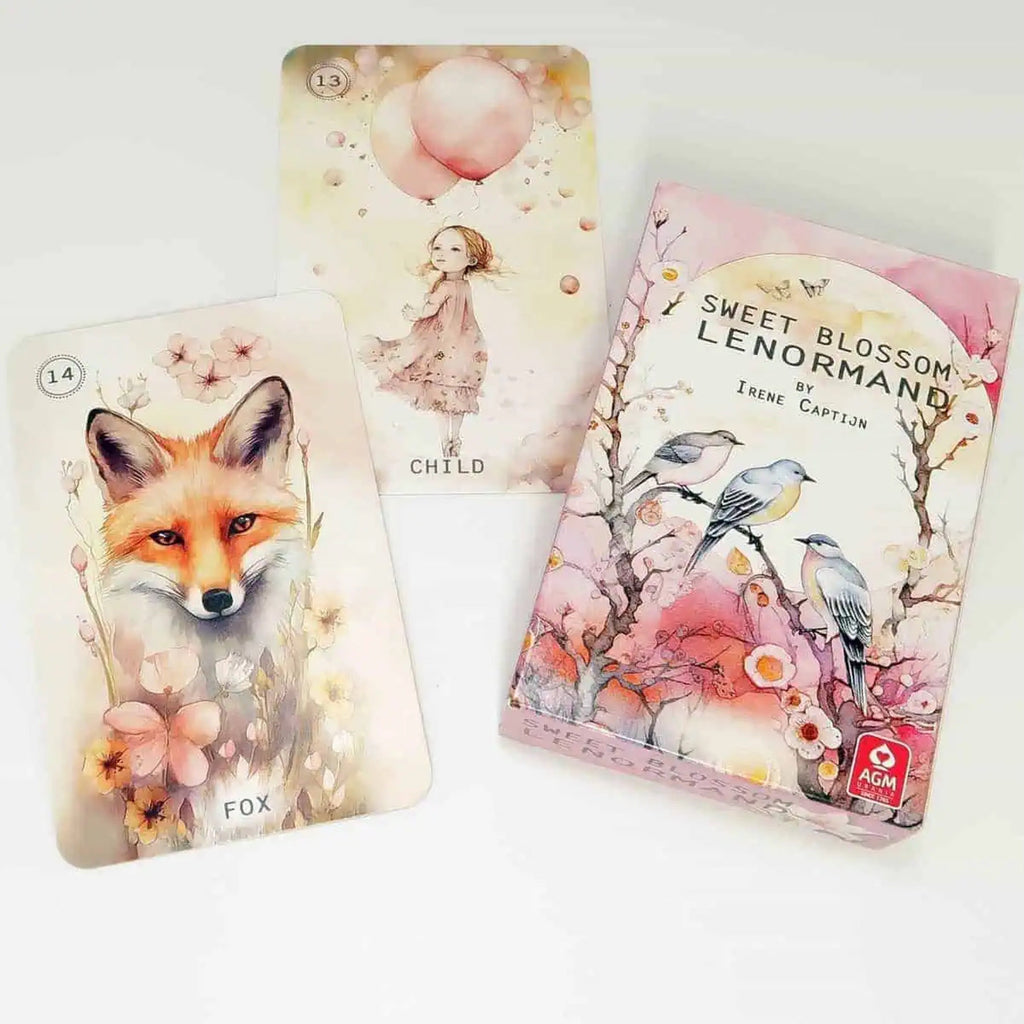 A Sweet Blossom Lenormand deck box and two illustrated cards displayed on a white background. The box features pink floral artwork with birds, and the cards show whimsical watercolor illustrations including a fox and a child.
