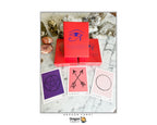 Dragon Tarot Oracle card deck set with a red box, three sample cards showing purple, pink, and pale pink designs, crystals, and a marble surface. Dragon Tarot branding is visible.