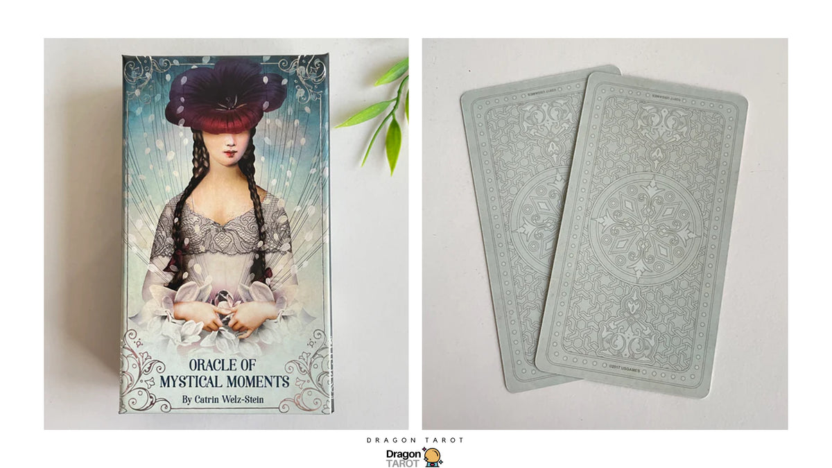 Oracle of Mystical Moments tarot deck by Carrie Wade-Stein, showing the illustrated front cover on the left and two back-facing cards with ornate pale blue-gray designs on the right, photographed on a light neutral background.