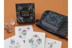 Trinity Tarot deck by Ali Memon displayed on an orange background, including the black illustrated box, a striped drawstring bag, and several white cards with line-art illustrations.