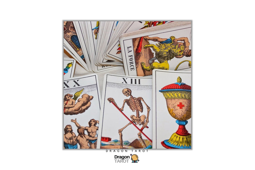 A set of illustrated tarot cards fanned out on a white background, with several cards fully visible including the Three of Swords, Eight of Cups, and The Hanged Man. The Dragon Tarot logo is visible at the bottom.