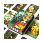 A boxed card deck titled "Dreaming Song" is shown on a white surface with several illustrated cards arranged around it. The box features fantasy-style artwork with a woman and warm glowing tones, and the cards also have detailed printed illustrations.