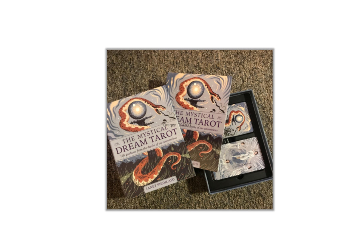The Mystical Dream Tarot deck displayed on a textured brown carpet, showing the illustrated outer box, the inner tray with cards, and the main tarot card deck.