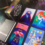 A set of illustrated tarot cards and a matching deck box arranged on a dark surface. The cards feature colorful fantasy-style artwork with figures, animals, and symbols, while the box has a black geometric dragon design.